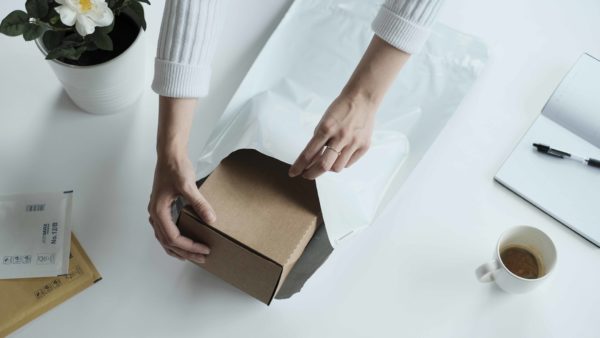 woman packing a brown box in a white mailing bag