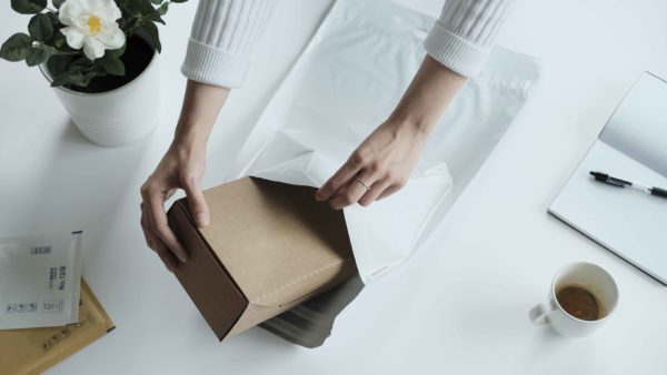 woman packing a box in a white mailing bag